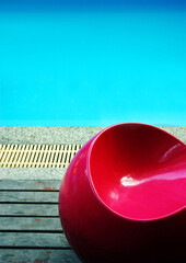 Bright red retro chair next to a swimming pool