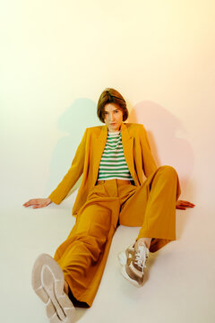 Female model in yellow suit leaning on floor