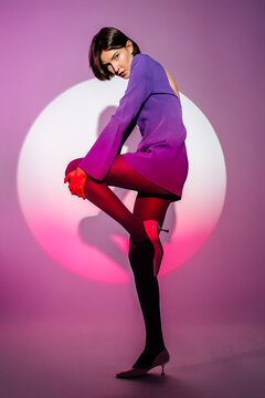 Woman in purple mini dress against round shaped illumination