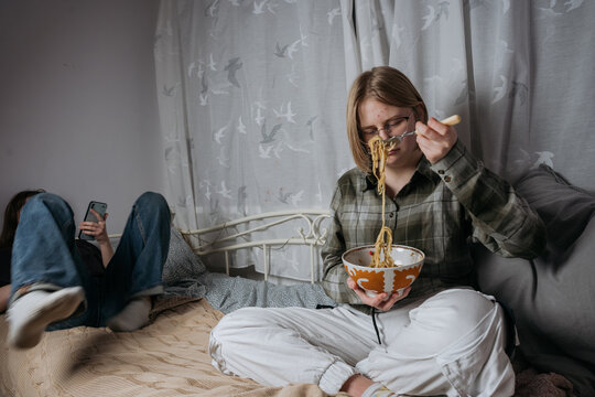 Teenager girl eating in her bedroom