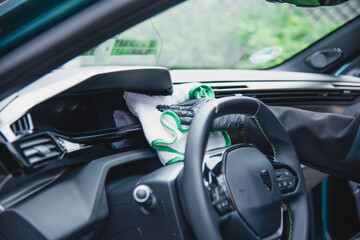 modern car dashboard is beeing carefully cleaned with a micro fiber towel from an professional car detailing service using gloves.. 