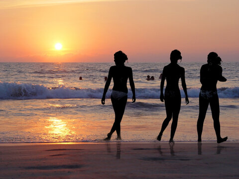 Girls' silhouettes on the beach at sunset