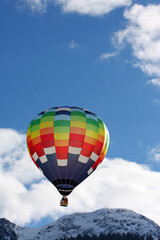 Colorful hot air balloon flying against a blue sky background
