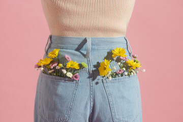 Woman with beautiful tender flowers in back pocket of her jeans out