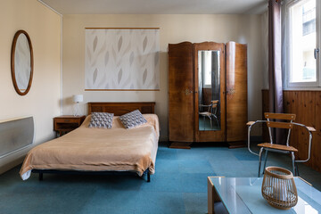 Bedroom with a vintage french wood wardrobe and carpet on the floor