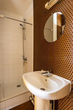 Minimalist toilet with polka dot wallpaper,  round mirror, shower box