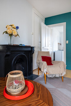 Coffee table with a candle over it next to black chimney and armchair