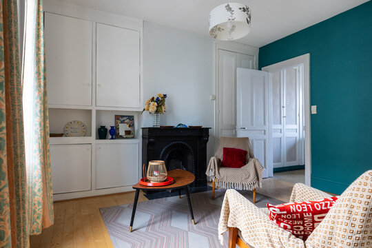 Living room in apartment with a chimney, armchair and green wall