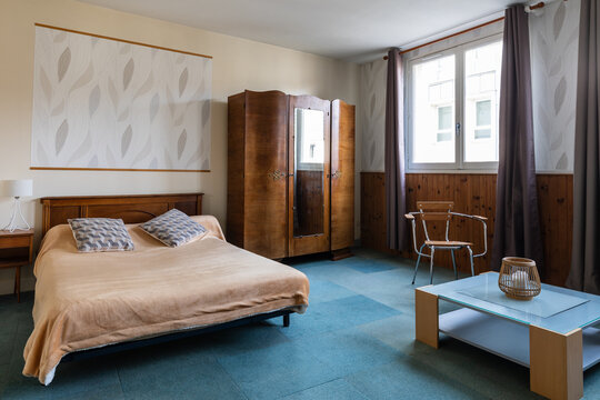 Bedroom with a blue carpet and a classic vintage wooden wardrobe 