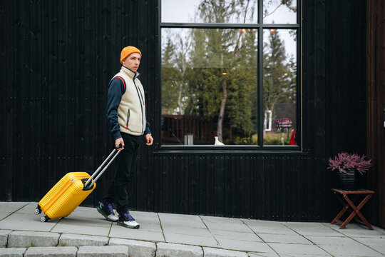 Young millennial man with yellow Luggage check out from hotel
