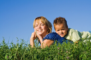 Fototapeta premium Boy outdoors on the grass with his mother in summer time