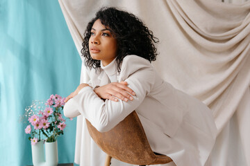 Black female with curly hair standing against curtains