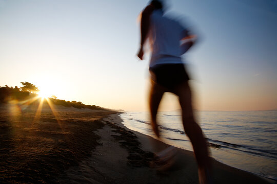 Young male runner running on a empty beach at dawn. Blur effect.