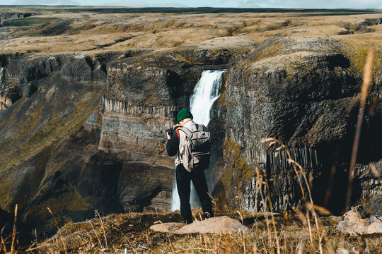 Male Hiker Photographing A Powerfull Waterfall in Highlands