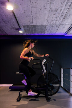 fit woman riding on air bicycle during cardio training in gym