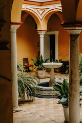 Fototapeta na wymiar Andalusian archway in vibrant colored patio with tiled Fountain