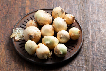 pile of onions on rustic wood, top view, space for text