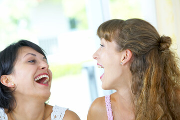 High key portrait of two young females laughing on something