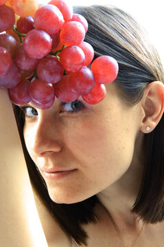 Beautiful young woman with red grape