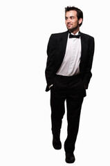 Full body of an attractive young brunette man with a beard wearing a black tuxedo stepping