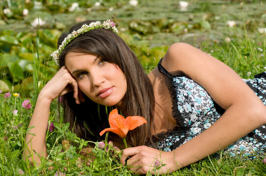 beautiful brunette outdoor with a flowers crown and an orange lily