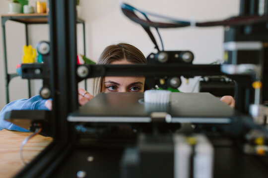 A woman looks at a 3D printer