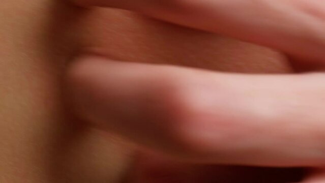 A woman's hand scratches a reddened inflamed place on the skin close-up. Itching, scabies, eczema