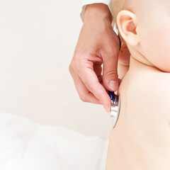 Obraz na płótnie Canvas Children's doctor exams infant with stethoscope