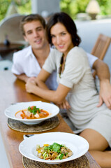 A young couple on vacation eating lunch at a relaxed outdoor restaurant (focus on food)