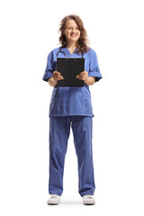 Female nurse in a blue uniform holding a clipboard and smiling