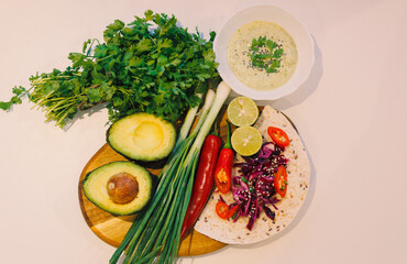 Charcuterie board, Vegetables (Avocado, red chili, lemon, tortilla, coriander, red cabbage ) Taco on a wooden tray with guacamole