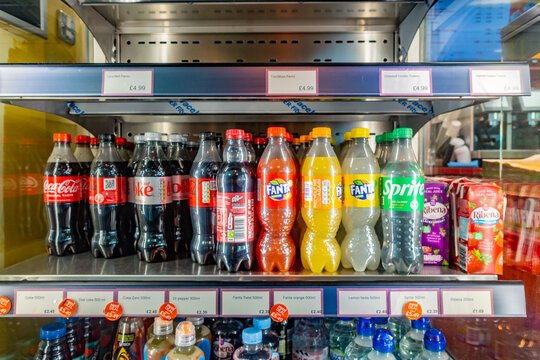 Carbonated soda drinks on sale on a shelf in a fridge in a shop