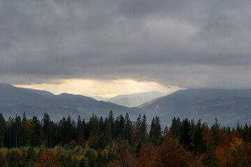 Naklejka na ściany i meble Autumn mountains under clouds, through which sun's rays break through. The beauty of the Carpathians. Tourism and travel