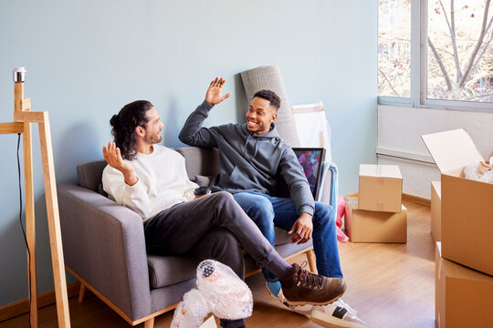 Happy male friends in new apartment
