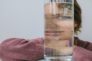 Beautiful woman looking through glass with water