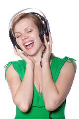 beautiful girl in a green dress singing to music with big headphones, isolated on white