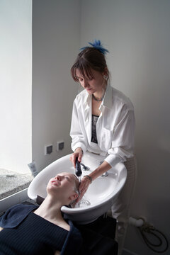 Female master washing head of salon client