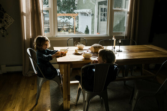 Two children sitting at dining table eating butternut squash soup 
