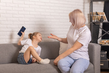 Digital detox. Mother taking smartphone from her little child. Children's gadget dependence,...