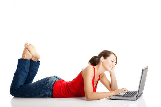 Beautiful and happy young woman lying on floor and working on a laptop