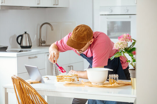 A man enthusiastically prepares a cake in his bright kitchen