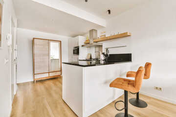 a kitchen and dining area in a house with wood flooring, white walls and wooden shelves on the wall