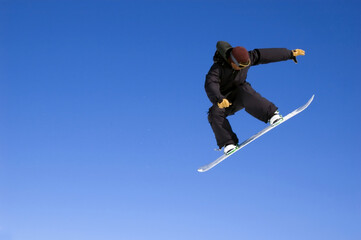 Fototapeta na wymiar a snowboarder jumping high through a blue sky