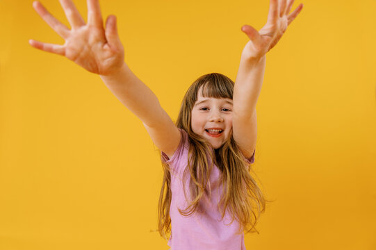 Happy cute toddler girl wearing violet shirt on yellow background