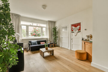 a living room with white walls and hardwood flooring, including a black leather couch in the center of the room