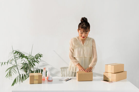 Small Asian business owner packaging beauty product in box
