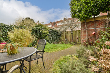 an outside area with a table, chairs and potted plants in the fore - image is taken from behind