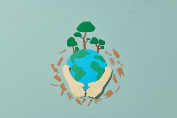 Hands holding paper earth on color background. World environment