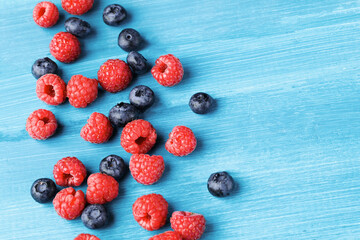 Raspberry and blueberry on blue background with copy space