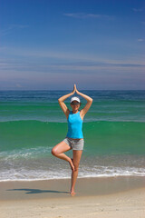 Beautiful woman making yoga exercises on the beach
